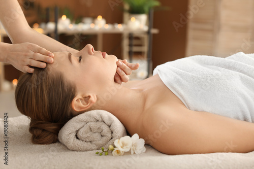 Young woman enjoying face massage in spa salon