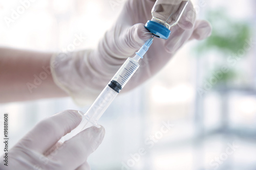 Doctor with syringe and medicine for vaccination on blurred background