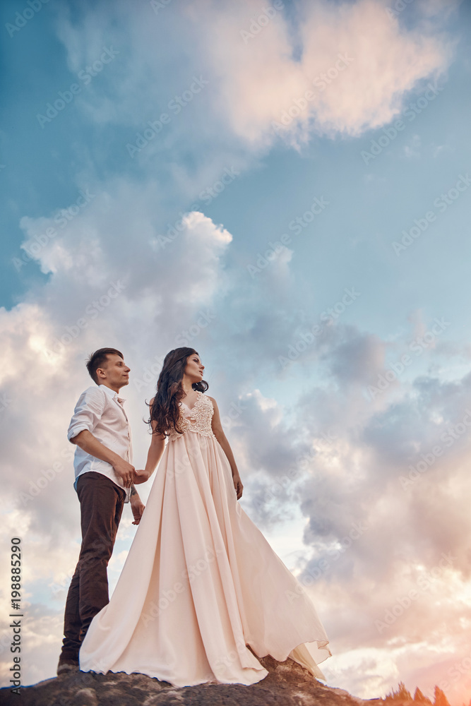 Love kiss and hugs in love couples at sunset in the evening sun, a walk through the mountains and hills. Sensual and gentle loving girl look, the sun rays Shine on the loving couple Love kiss and hugs in love couples at sunset in the evening sun, a walk through the mountains and hills. Sensual and gentle loving girl look, the sun rays Shine on the loving couple