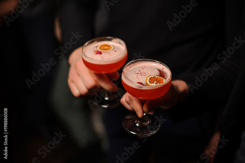 Two people holding cocktail glasses with sweet alcoholic drink