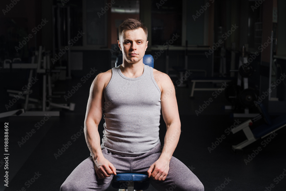 Strong handsome fit man exercising in the gym. Personal trainer workout. Athletic man working out his chest with dumbbells on a bench. Fitness, healhty lifestyle, bodybuilding concept.