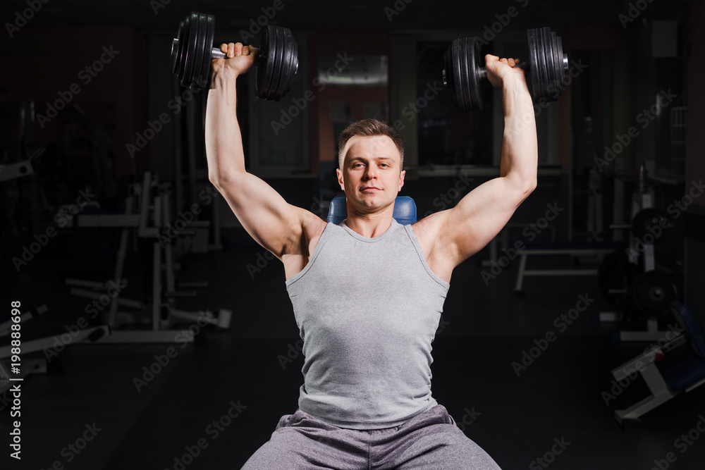 Strong handsome fit man exercising in the gym. Personal trainer workout. Athletic man working out his chest with dumbbells on a bench. Fitness, healhty lifestyle, bodybuilding concept. Strong handsome fit man exercising in the gym. Personal trainer workout. Athletic man working out his chest with dumbbells on a bench. Fitness, healhty lifestyle, bodybuilding concept.