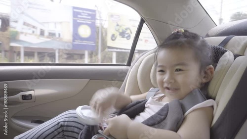Portrait of cute toddler asian girl sitting in car seat. Child transportation safety