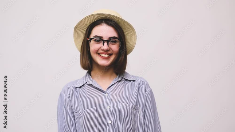 Happy cheerful young woman with hat and glasses showing thumbs up gesture isolated over white background Happy cheerful young woman with hat and glasses showing thumbs up gesture isolated over white background