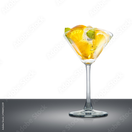 Mojito cocktail in martini glass with mint, orange and ice cubes on mirror table and place for inscription. Clipping path