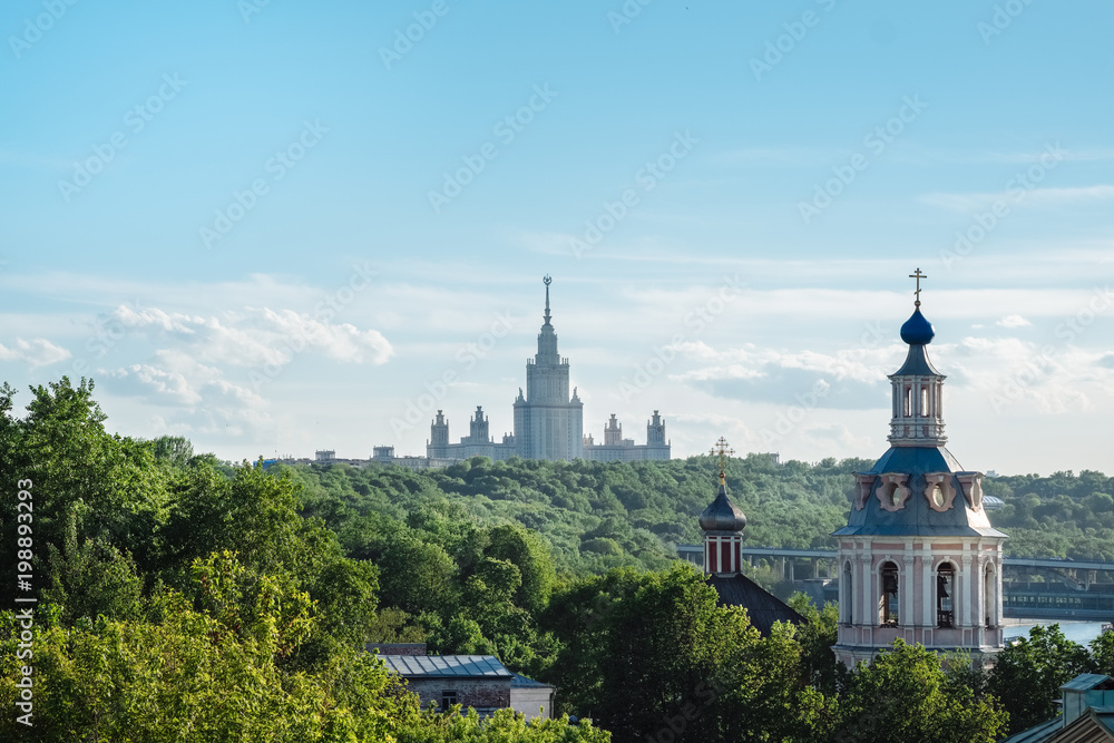 The buildings of Moscow city center with State University silhouette, some classical old church and colorful roofs. Beautiful city view of Moscow lush green nature, outdoor summer evening in Russia.