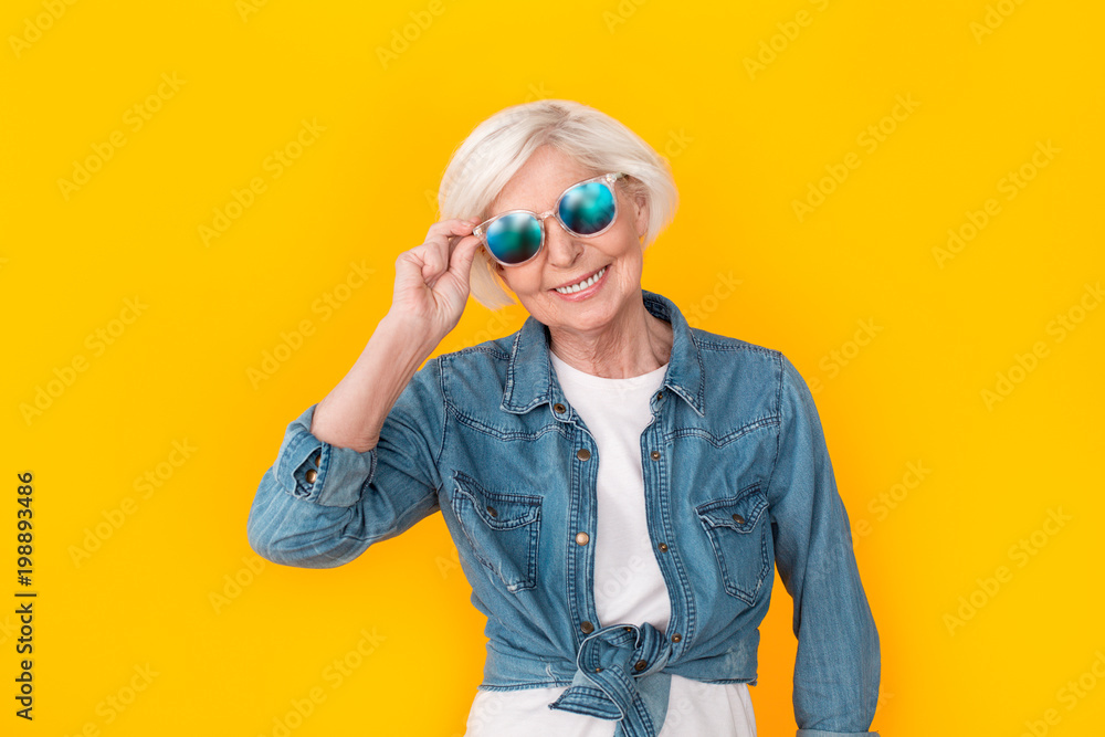 Senior woman traveler studio isolated on yellow wall wearing sunglasses Senior woman traveler studio isolated on yellow wall wearing sunglasses