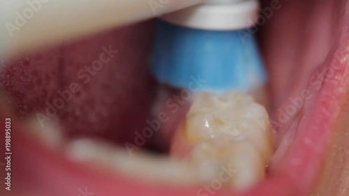 Close up of a man brushing his teeth with an electric toothbrush
