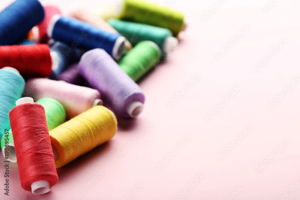 Colourful thread spools on pink background Colourful thread spools on pink background