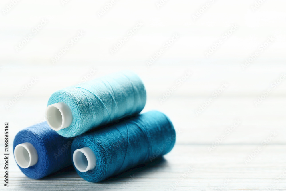 Colourful thread spools on white wooden table Colourful thread spools on white wooden table