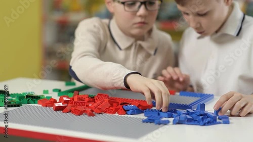 Two boys erect buildings from a children's plastic designer photo