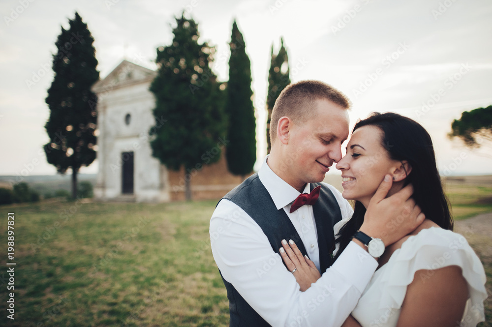 Happy stylish smiling couple walking in Tuscany, Italy on their Happy stylish smiling couple walking in Tuscany, Italy on their