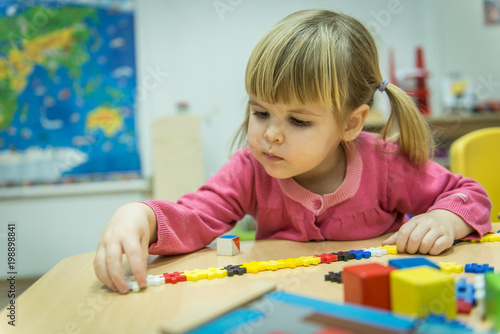Curiously kid playin with puzzle toy in kindergarten
