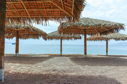 Fototapeta Naklejka Na Ścianę i Meble -  Beautiful public sandy beaches on Red Sea in Eilat with stro umbrellas, luxury vacation spa resorts in Israel