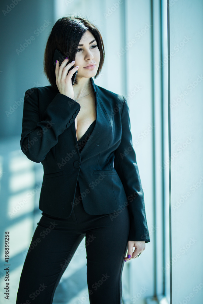 Business woman speak phone near panoramic windows in office. Business woman speak phone near panoramic windows in office.