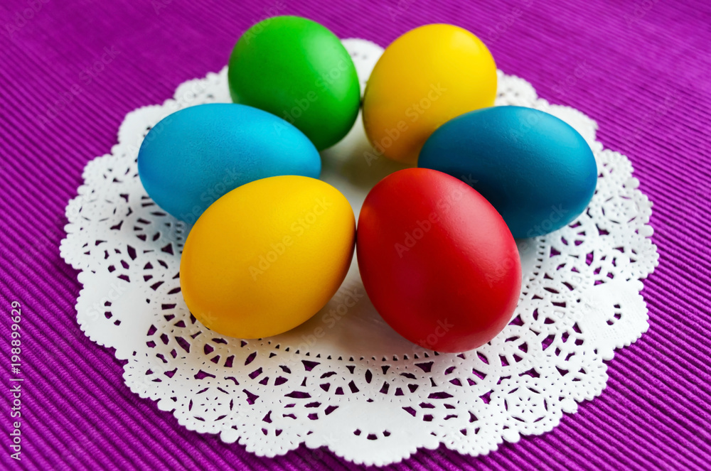Colorful eggs for holiday Easter on a white napkin on a vivid background.