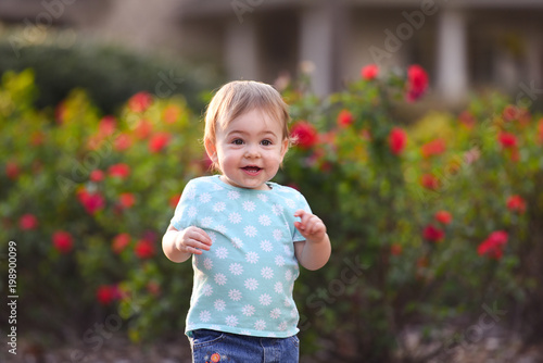Cute toddler girl outdoor in a rose garden running around happily