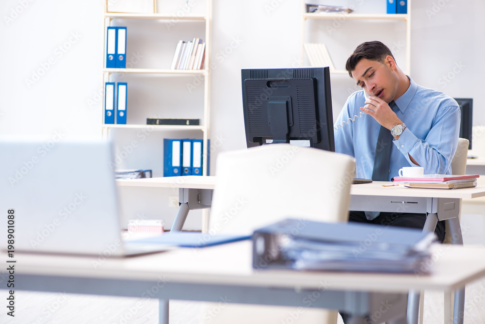 Handsome businessman employee sitting at his desk in office Handsome businessman employee sitting at his desk in office