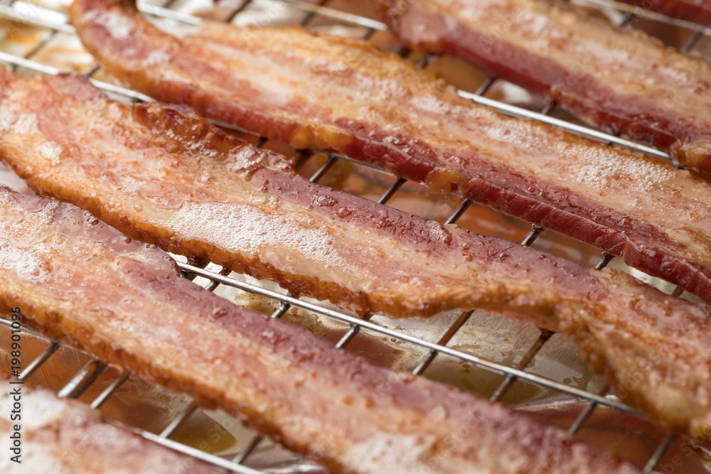 Macro close up on fried bacon strips on a metal cooling rack