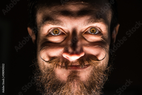 Inventor Hipster with Beard and Mustages in the Dark Room. Smiling Trickster. photo