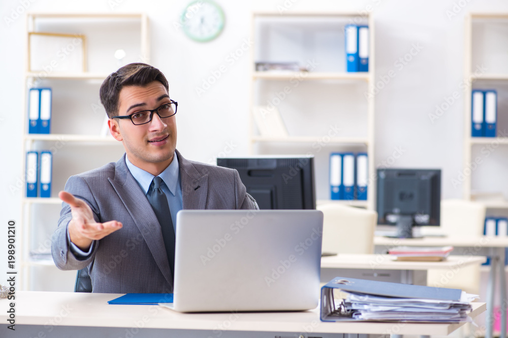 Handsome businessman employee sitting at his desk in office Handsome businessman employee sitting at his desk in office