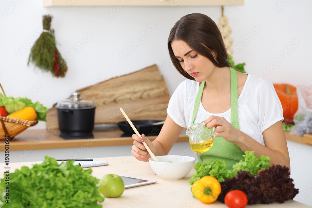 Beautiful Hispanic or latin american woman is holding wooden spoon while cooking in the kitchen. Beautiful Hispanic or latin american woman is holding wooden spoon while cooking in the kitchen.