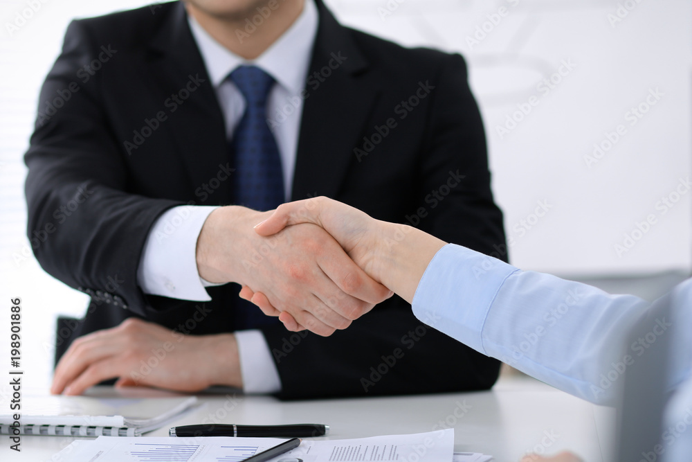 Close Up of unknown business people shaking hands while finishing up a meeting. Handshaking, agreement or success concept in people communication