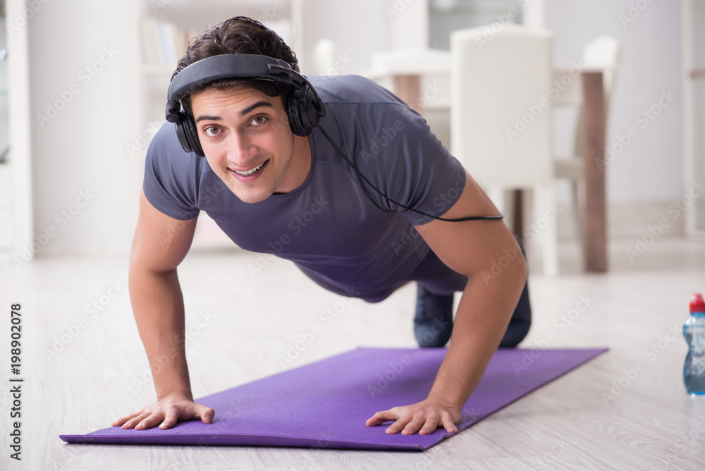 Fototapeta premium Man doing sports at home and listening to music