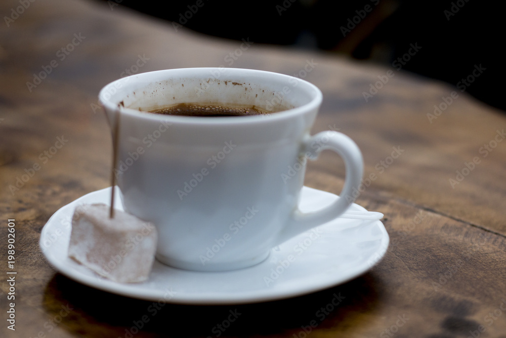 Cup of Turkish coffee served with locum with tootpick in it, wood table, dark background and great contrast Cup of Turkish coffee served with locum with tootpick in it, wood table, dark background and great contrast