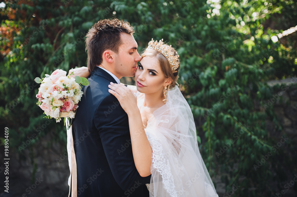 The groom gently kisses his beautiful bride. Young fashionable bride. Wedding. The groom gently kisses his beautiful bride. Young fashionable bride. Wedding.