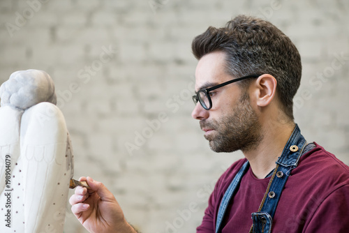 Portrait of Ceramist Dressed in an Apron Working on Clay Sculpture in Bright Ceramic Workshop. photo