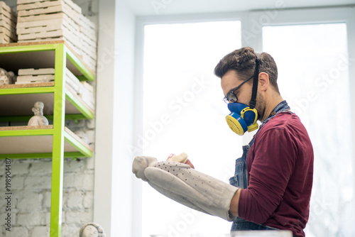 Portrait of Ceramist Dressed in an Apron Working on Clay Sculpture in Bright Ceramic Workshop. photo