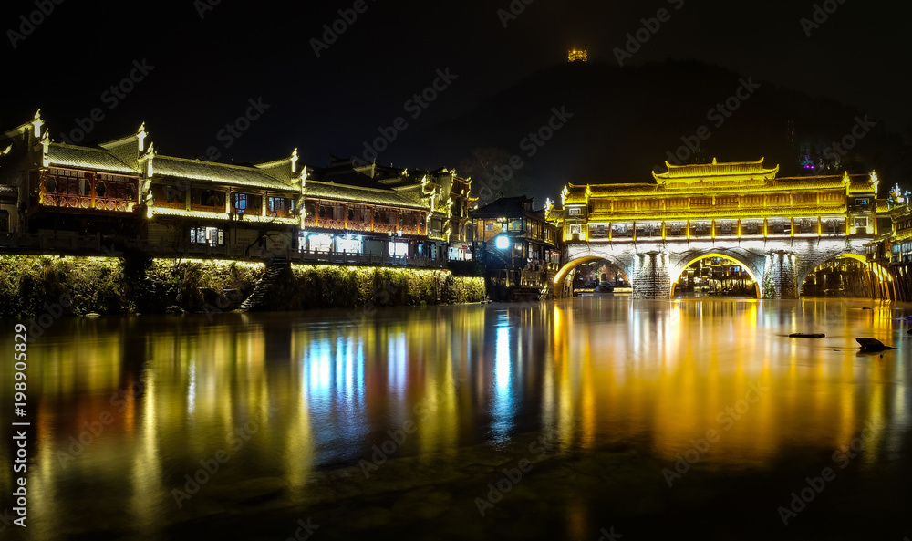 Fenghuang, phoenix ancient town, night view with reflections of the town on the river