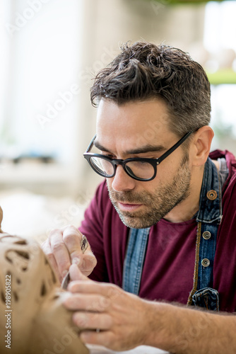 Ceramist Dressed in an Apron Sculpting Statue from Raw Clay in Bright Ceramic Workshop. photo