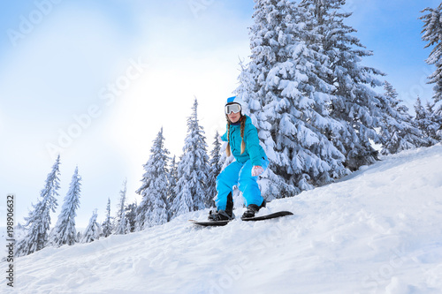 Female snowboarder on ski piste at snowy resort. Winter vacation