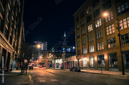 Chicago city street night scene in the West Loop with the skyline and Sears Willis Tower skyscraper in the background