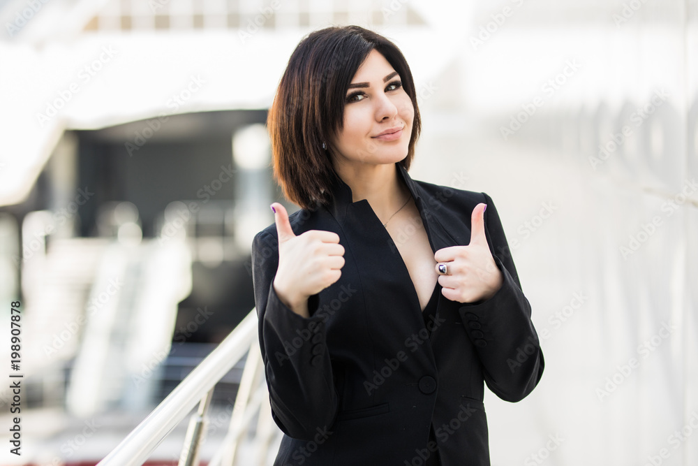 Happy businesswoman showing thumb up in office