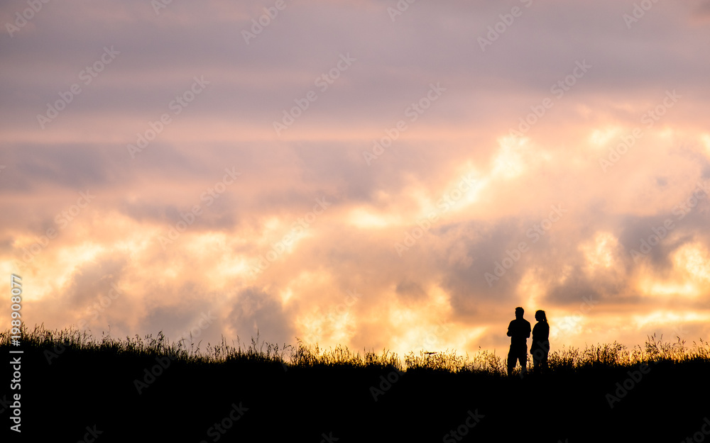 Silhouette scene of a couple enjoy with their drone at sunset on the top of Mt. Eden, Auckland, New Zealand.