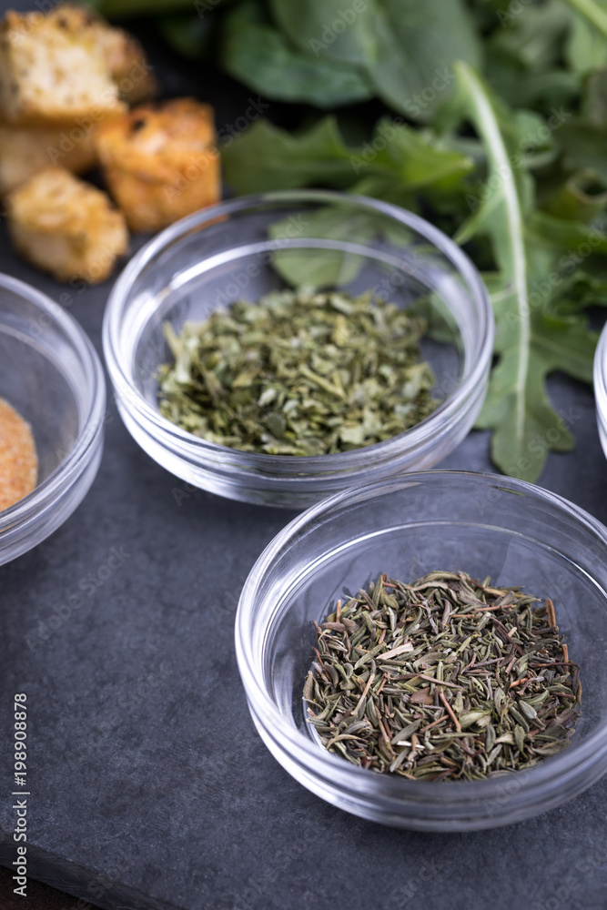 Glass ingredient dishes of dried thyme and parsley seasoning