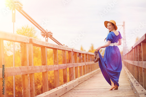 Young beautiful girl in dresses on nature. A girl in a hat walks