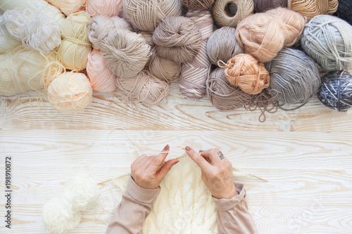 Wool and cotton yarn for knitting of neutral natural color. The woman knits knitting. photo