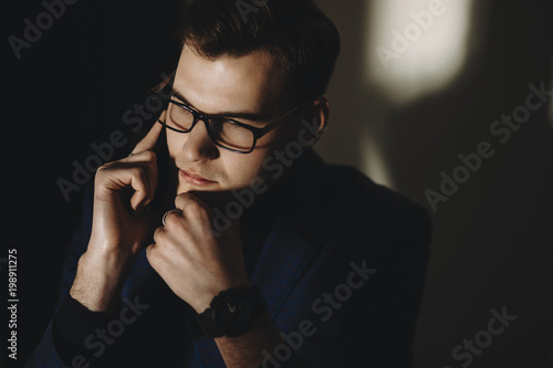 Confident and pensive man speaking on mobile phone dressed in a suit.Businessman speaking on phone with an amazing sunlight. photo