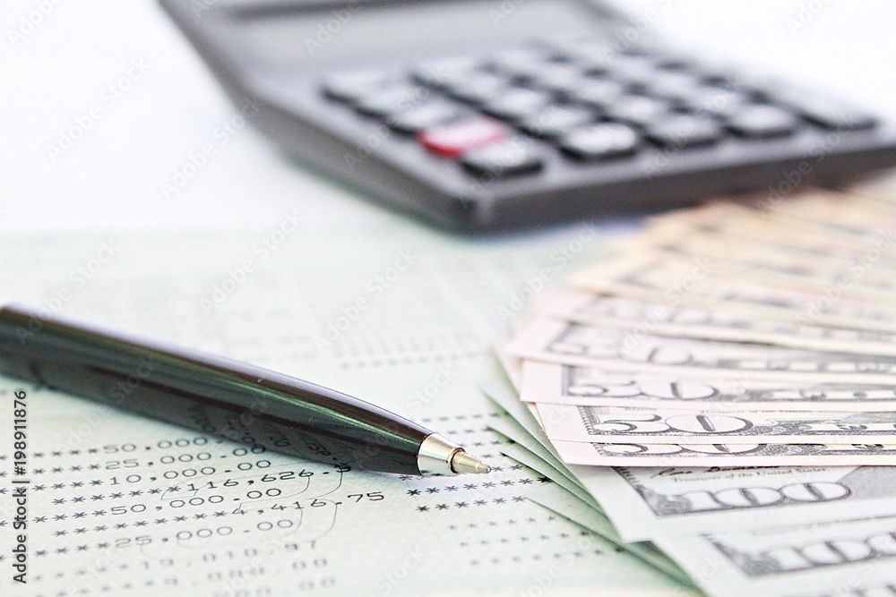 Business, finance, investment, accounting or money exchange concept : American Dollars cash money, calculator on savings account passbook or financial statement Business, finance, investment, accounting or money exchange concept : American Dollars cash money, calculator on savings account passbook or financial statement