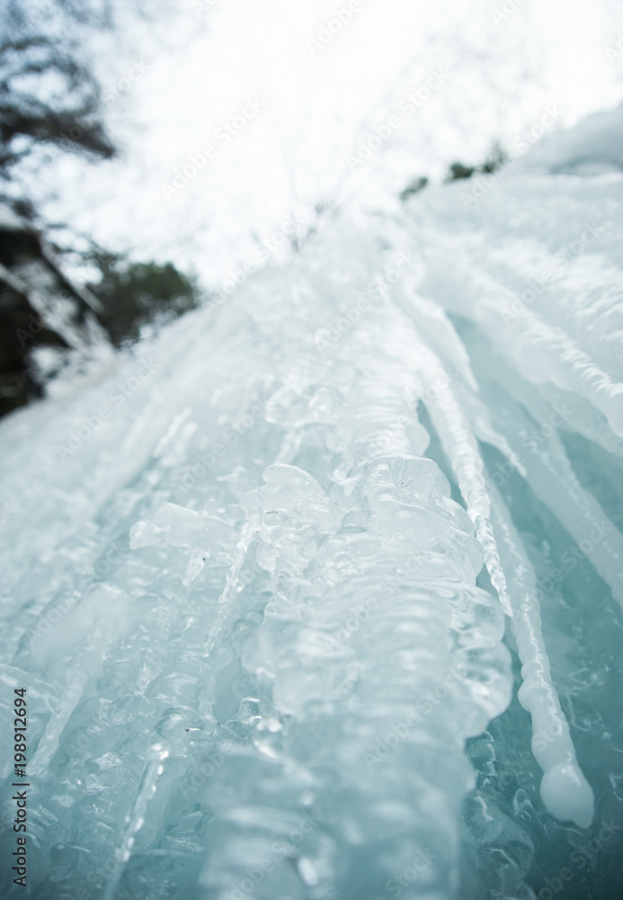 Fototapeta premium Detail of ice on a frozen waterfall in Pennsylvania shot looking up at the icicles. Unique ice formations in nature.