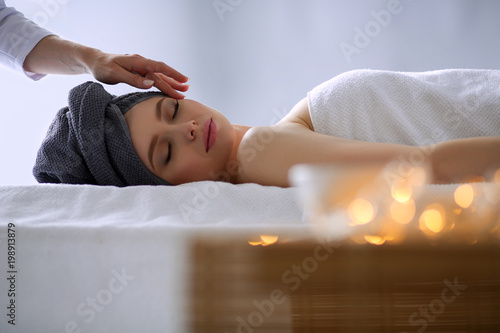 Young woman lying on a massage table,relaxing with eyes closed. Woman. Spa salon