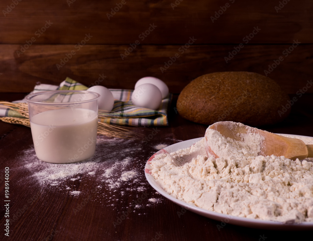 Flour, eggs, milk on a wooden background. Preparation of the dough. Flour, eggs, milk on a wooden background. Preparation of the dough.