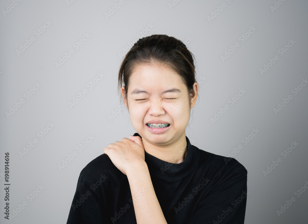 Asian girl in black casual dress catch that shoulder, Because of the pain of hard work. Or something hit the shoulder. on a gray background gives a soft light. Asian girl in black casual dress catch that shoulder, Because of the pain of hard work. Or something hit the shoulder. on a gray background gives a soft light.