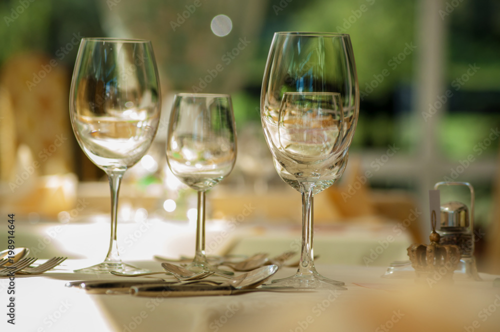 Empty wine and water glasses in the restaurant with Bokeh in the background.