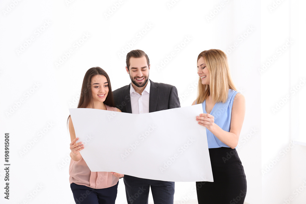 Real estate agent with trainee showing plan of apartment to client Real estate agent with trainee showing plan of apartment to client
