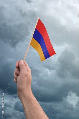 Armenia flag held by a hand in front of a cloudy stormy sky
